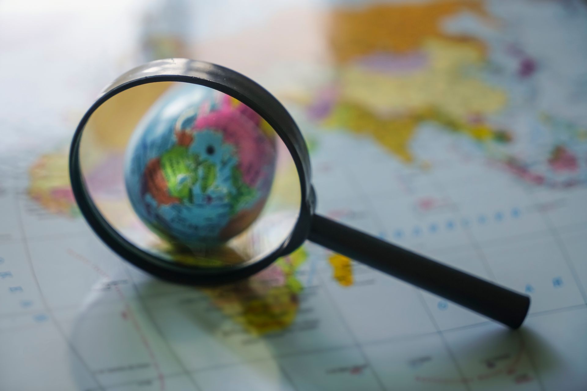 Magnifying glass close up with colorful map and globe 