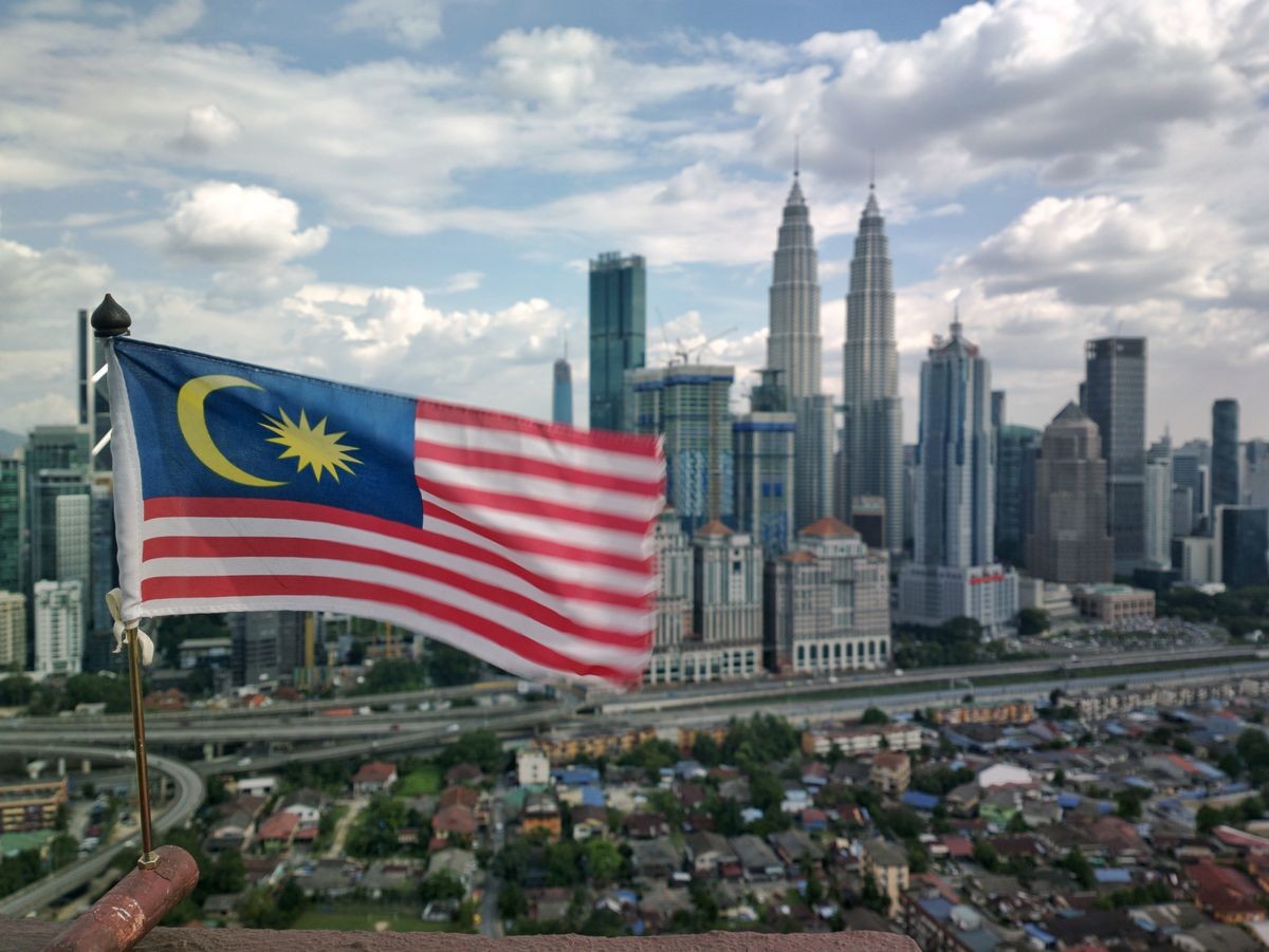 Malaysia flag at high altitude with Kuala Lumpur background at noon. The wind blows on the flag.